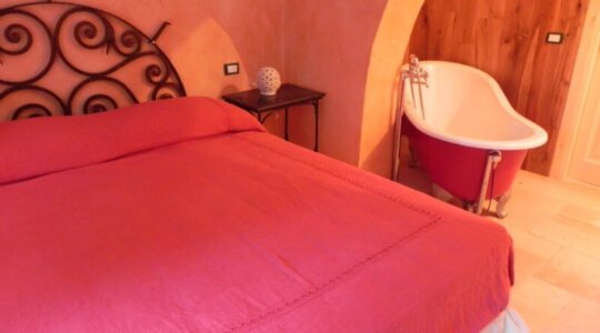 Een slaapkamer met bad van naturistische accommodatie Locanda di Terramare