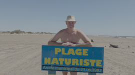 Bloot recreant achter bord Naaktstrand op Plage de Piémanson