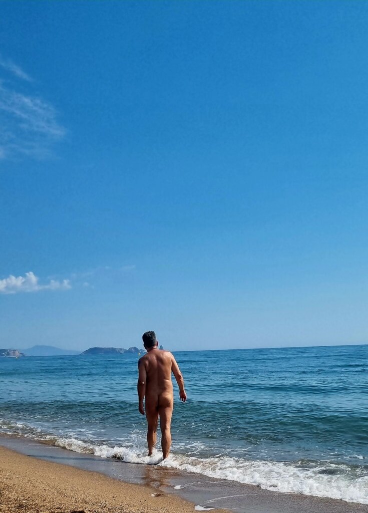 blote man wandelt door de branding op naaktstrand platja de pals