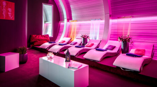 Mooie ligbedden in roze licht op BLUE Wellnessresort Sittard